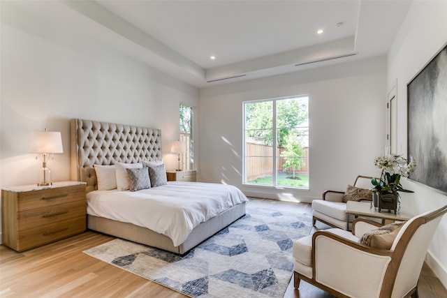 bedroom featuring a raised ceiling and light wood-type flooring