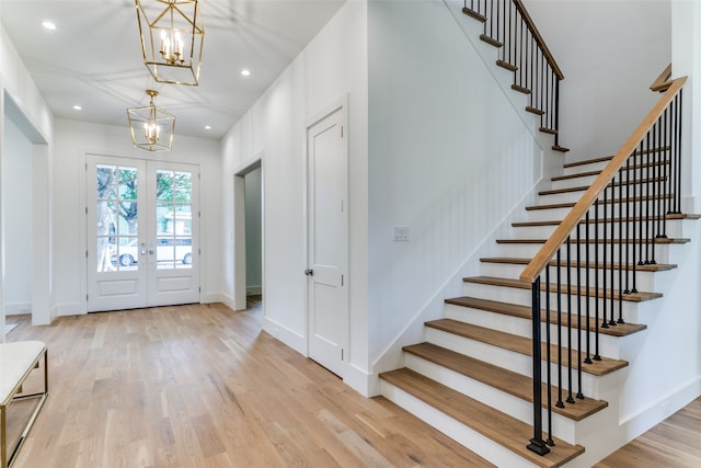 entrance foyer featuring french doors, a chandelier, and light wood-type flooring