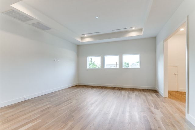 spare room featuring light hardwood / wood-style floors and a tray ceiling