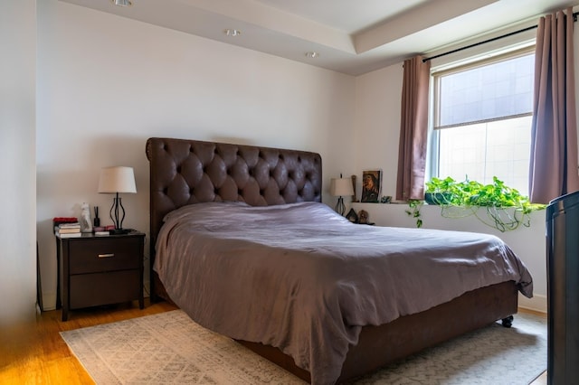 bedroom featuring light hardwood / wood-style flooring and a tray ceiling