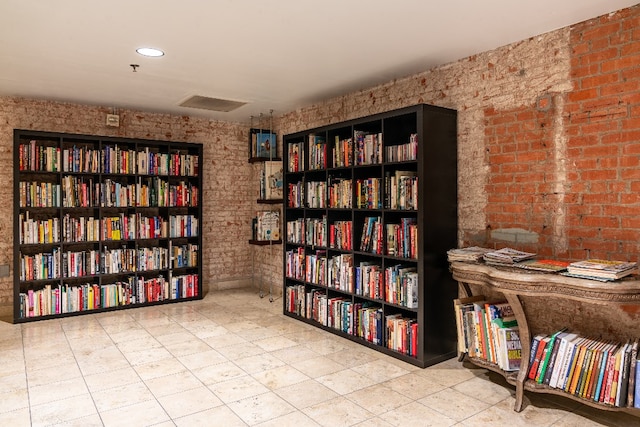 sitting room with brick wall and light tile floors