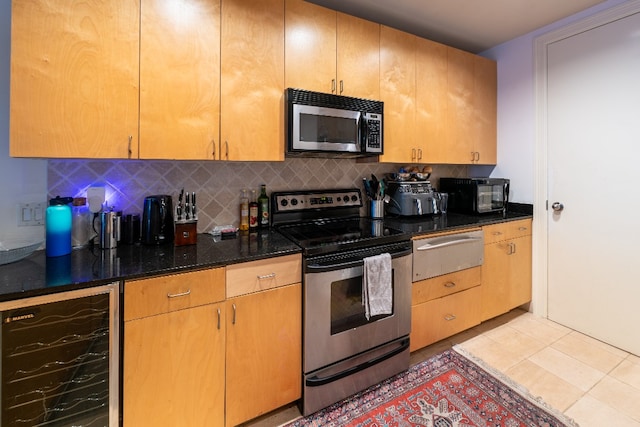 kitchen featuring light tile flooring, beverage cooler, backsplash, stainless steel appliances, and dark stone countertops