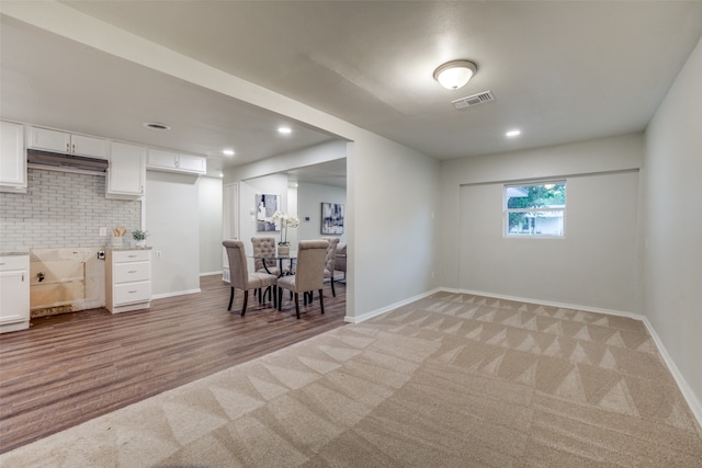 interior space featuring tasteful backsplash, white cabinets, and carpet floors