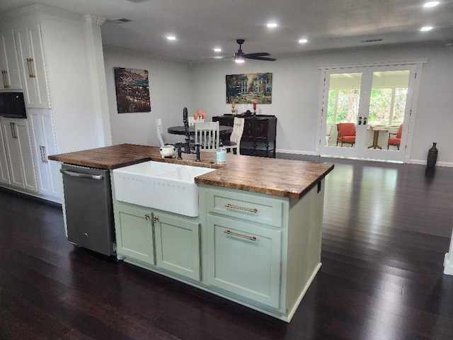 kitchen featuring butcher block countertops, dark wood-type flooring, white cabinetry, a center island with sink, and stainless steel dishwasher