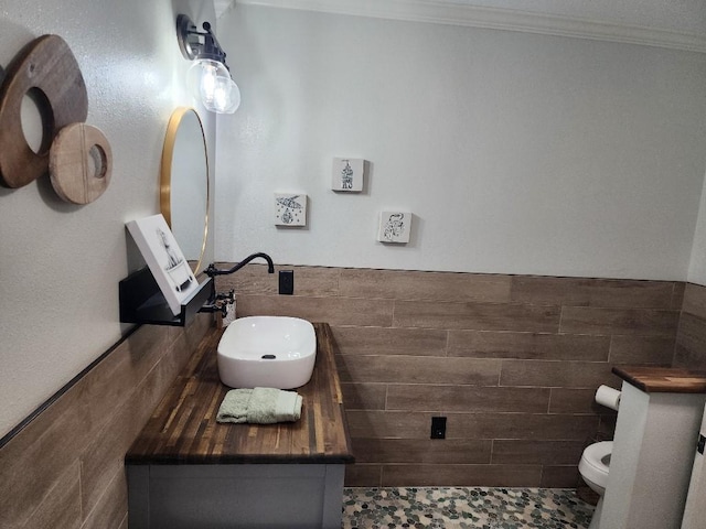 bathroom featuring tile walls, vanity, ornamental molding, and toilet