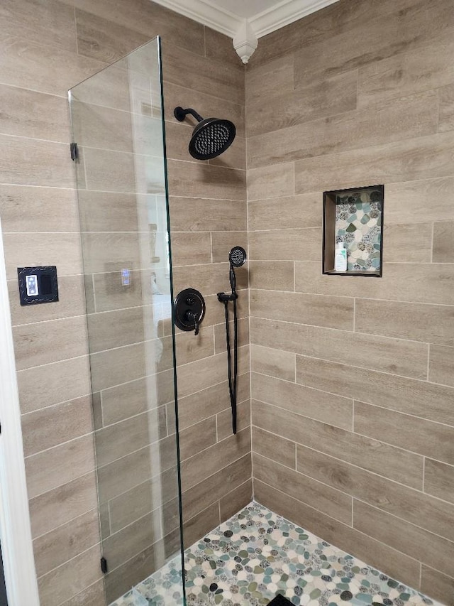 bathroom with crown molding and a tile shower