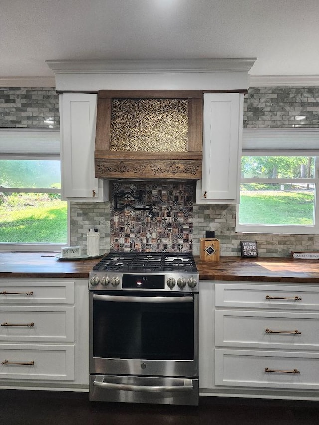 kitchen with gas stove, premium range hood, crown molding, and butcher block counters