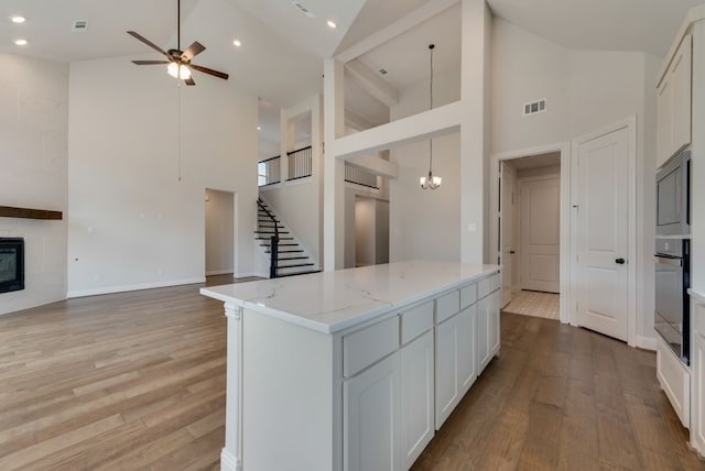 kitchen with light stone counters, visible vents, a premium fireplace, oven, and open floor plan