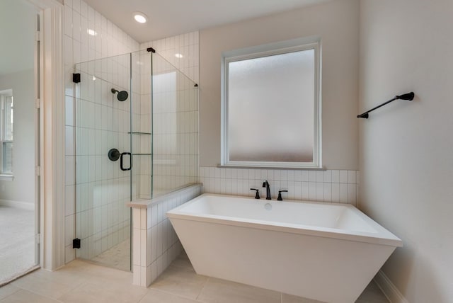 bathroom with tile patterned flooring, a stall shower, a freestanding bath, and tile walls