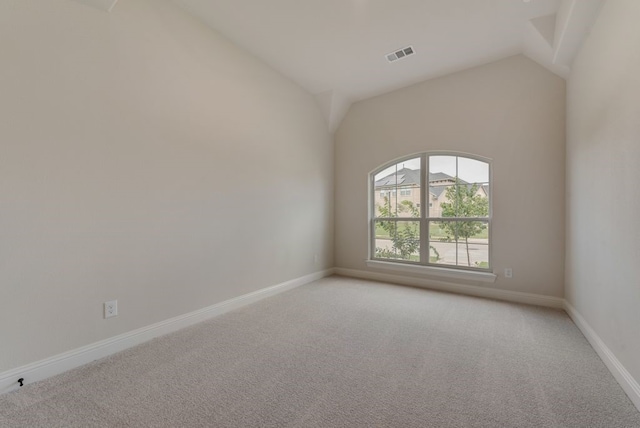 spare room with visible vents, light colored carpet, baseboards, and vaulted ceiling