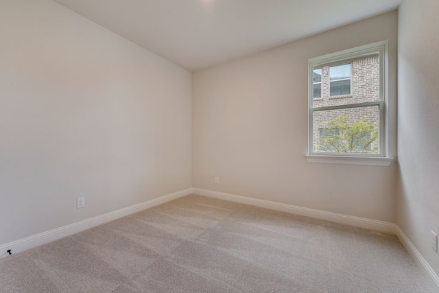 spare room with baseboards and light carpet