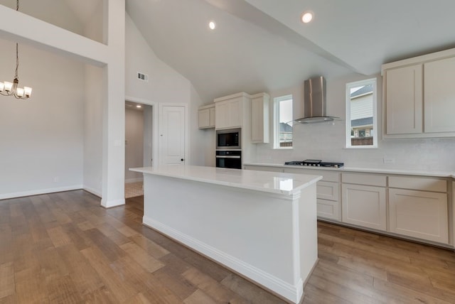 kitchen featuring visible vents, stainless steel appliances, wall chimney exhaust hood, and light countertops