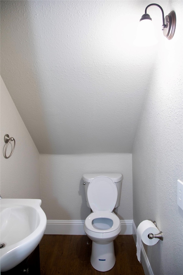 bathroom with hardwood / wood-style floors, vaulted ceiling, sink, and toilet