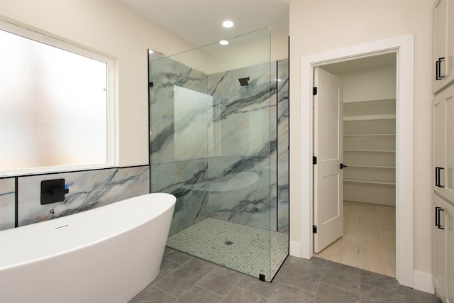 full bath featuring a spacious closet, recessed lighting, a marble finish shower, and a freestanding bath