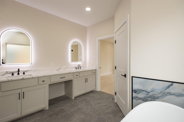 bathroom featuring double vanity, a soaking tub, recessed lighting, and a sink