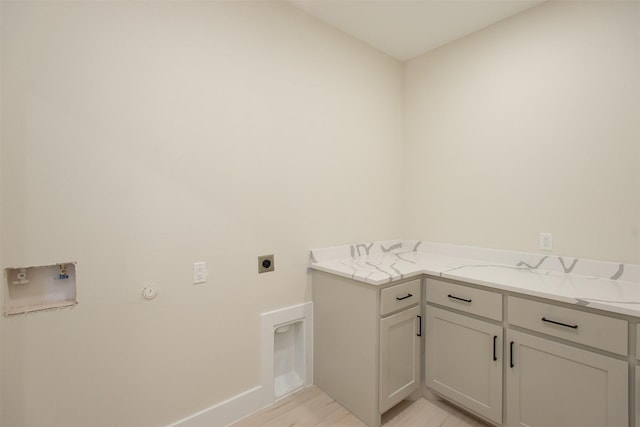 washroom with cabinet space, electric dryer hookup, washer hookup, light wood-style floors, and hookup for a gas dryer