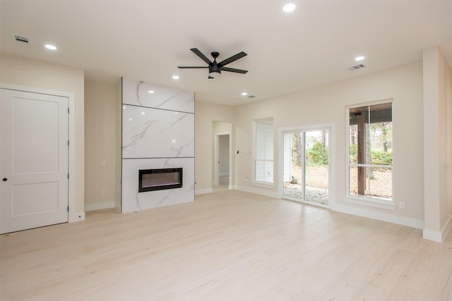 unfurnished living room featuring a high end fireplace, recessed lighting, and light wood-style floors