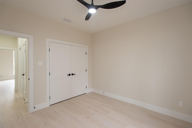 unfurnished bedroom featuring baseboards, visible vents, light wood finished floors, ceiling fan, and a closet