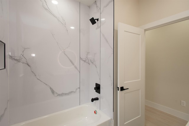 bathroom featuring a combined bath / shower with marble appearance, baseboards, and wood finished floors