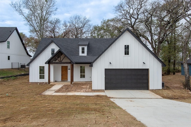 modern farmhouse featuring board and batten siding, concrete driveway, a garage, and a shingled roof