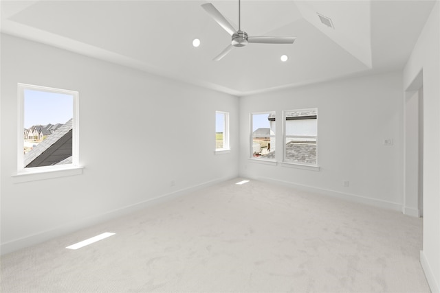 empty room featuring light carpet, a tray ceiling, and ceiling fan