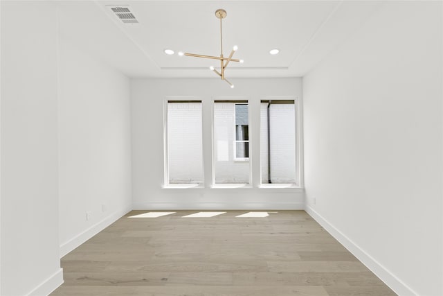 spare room featuring light hardwood / wood-style floors and a notable chandelier