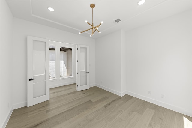 spare room featuring light hardwood / wood-style flooring and a notable chandelier