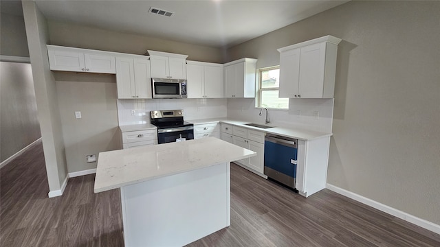 kitchen featuring appliances with stainless steel finishes, tasteful backsplash, white cabinets, sink, and dark hardwood / wood-style flooring