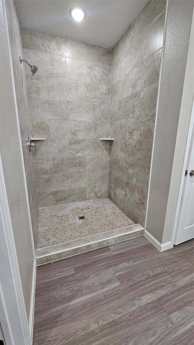 bathroom featuring wood-type flooring and tiled shower