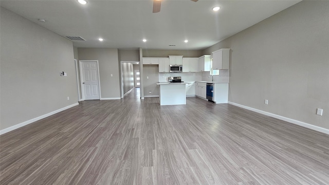 unfurnished living room with wood-type flooring, sink, and ceiling fan