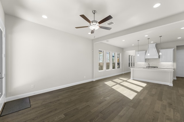 unfurnished living room featuring ceiling fan, dark hardwood / wood-style flooring, and sink