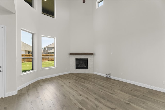 unfurnished living room with a towering ceiling, light wood-type flooring, and ceiling fan