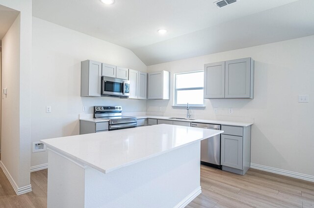 kitchen featuring gray cabinets, stainless steel appliances, sink, a breakfast bar, and light hardwood / wood-style flooring