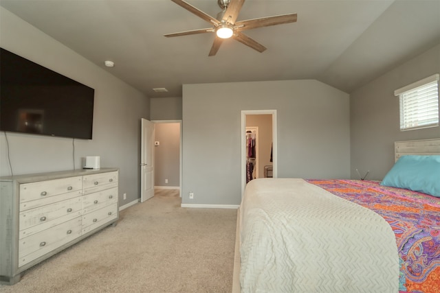 carpeted bedroom featuring ceiling fan, vaulted ceiling, and a walk in closet