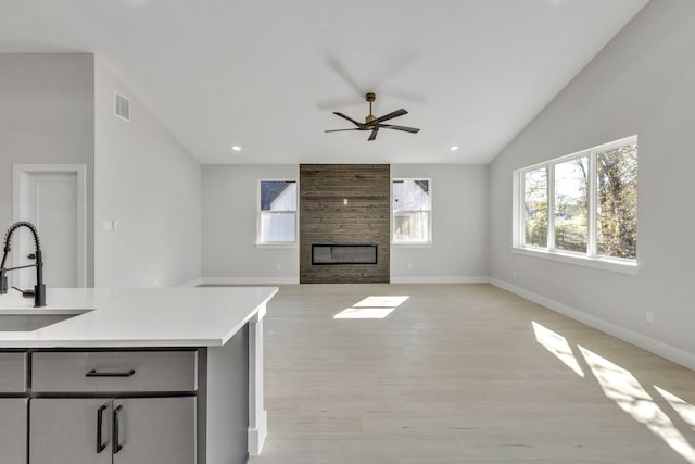 kitchen featuring sink, light hardwood / wood-style flooring, ceiling fan, and a large fireplace