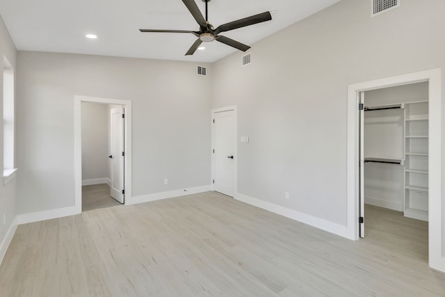 unfurnished bedroom with a spacious closet, a closet, light wood-type flooring, ceiling fan, and ensuite bathroom