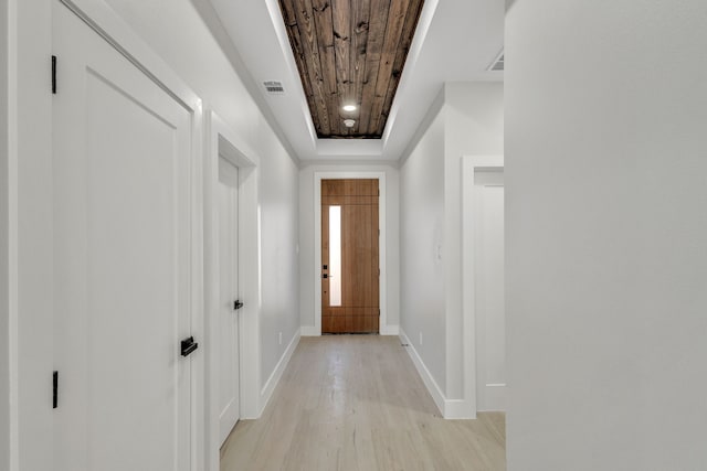 doorway to outside with wood ceiling, light hardwood / wood-style flooring, and a tray ceiling