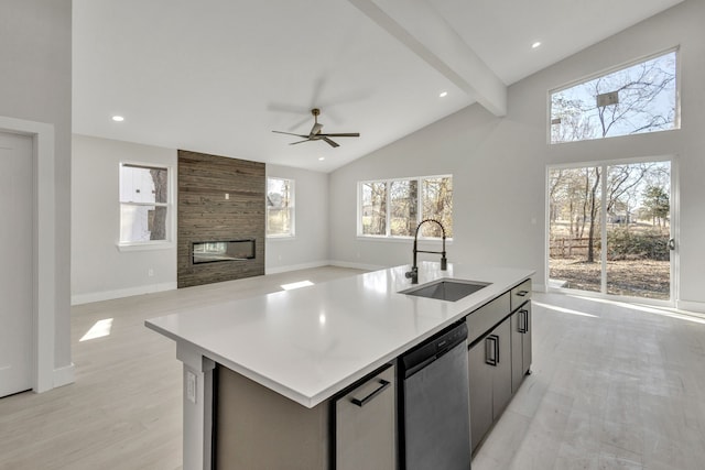 kitchen featuring beamed ceiling, stainless steel dishwasher, sink, a center island with sink, and plenty of natural light