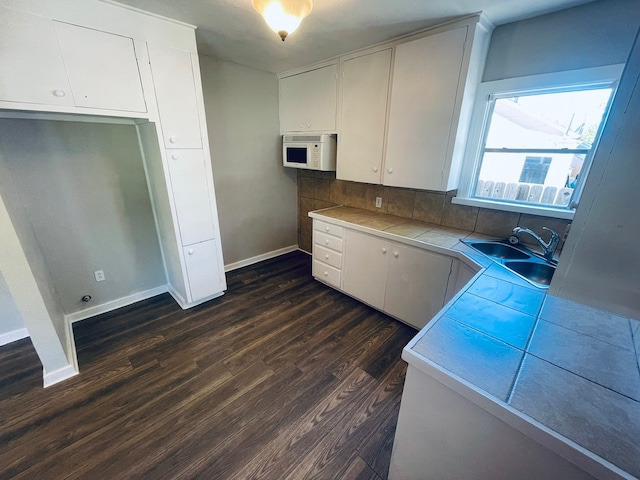 kitchen featuring sink, backsplash, white cabinetry, dark hardwood / wood-style floors, and tile countertops