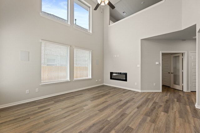 unfurnished living room with ceiling fan, high vaulted ceiling, hardwood / wood-style floors, and a healthy amount of sunlight