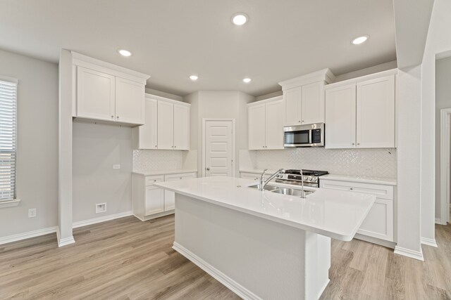 kitchen with light hardwood / wood-style floors, backsplash, stainless steel appliances, and white cabinetry