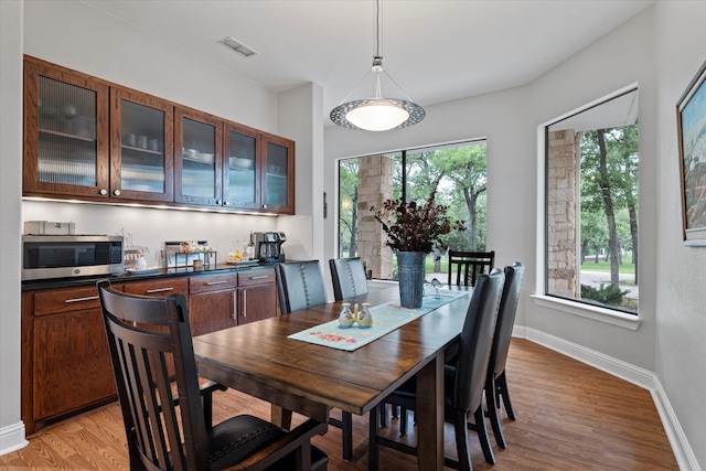 dining room featuring light wood-style flooring, visible vents, and baseboards