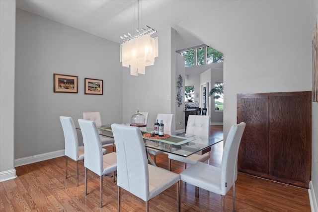 dining area with a high ceiling, baseboards, and wood finished floors