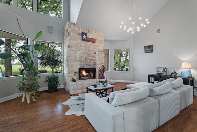 living room featuring baseboards, visible vents, wood finished floors, a stone fireplace, and high vaulted ceiling