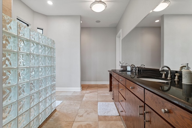 bathroom with double vanity, tile patterned flooring, baseboards, and a sink