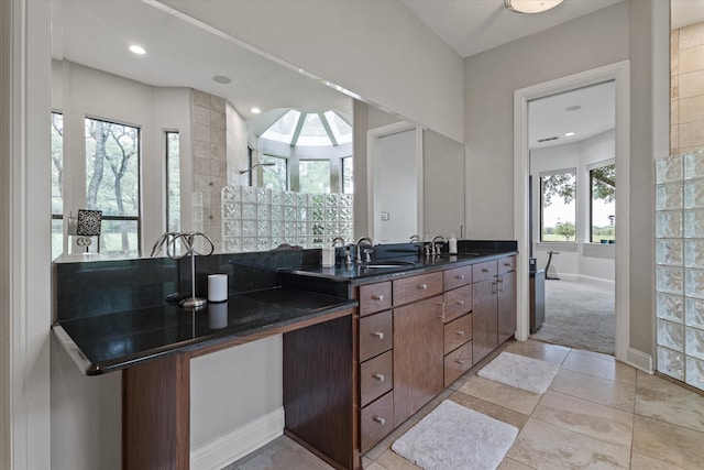 full bath featuring a walk in shower, double vanity, a sink, and baseboards