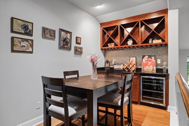 interior space with wine cooler, tasteful backsplash, light wood-style floors, a bar, and baseboards