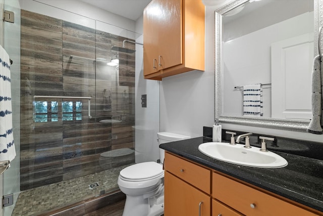 bathroom featuring a shower stall, toilet, and vanity