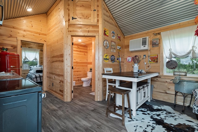 kitchen with dark wood-type flooring, vaulted ceiling, wood walls, and a wall mounted AC