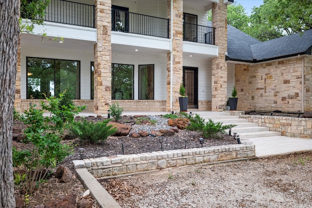 property entrance with stone siding and roof with shingles